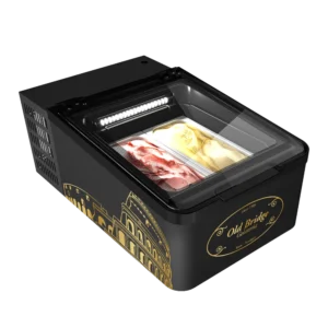 Das Bild zeigt eine Mini-Eistruhe im Old-Bridge-Design – kompakt, mit Glasdeckel und integrierter LED-Beleuchtung. Sichtbare Gelato-Schalen, schwarzes Gehäuse mit goldenen Markenelementen.